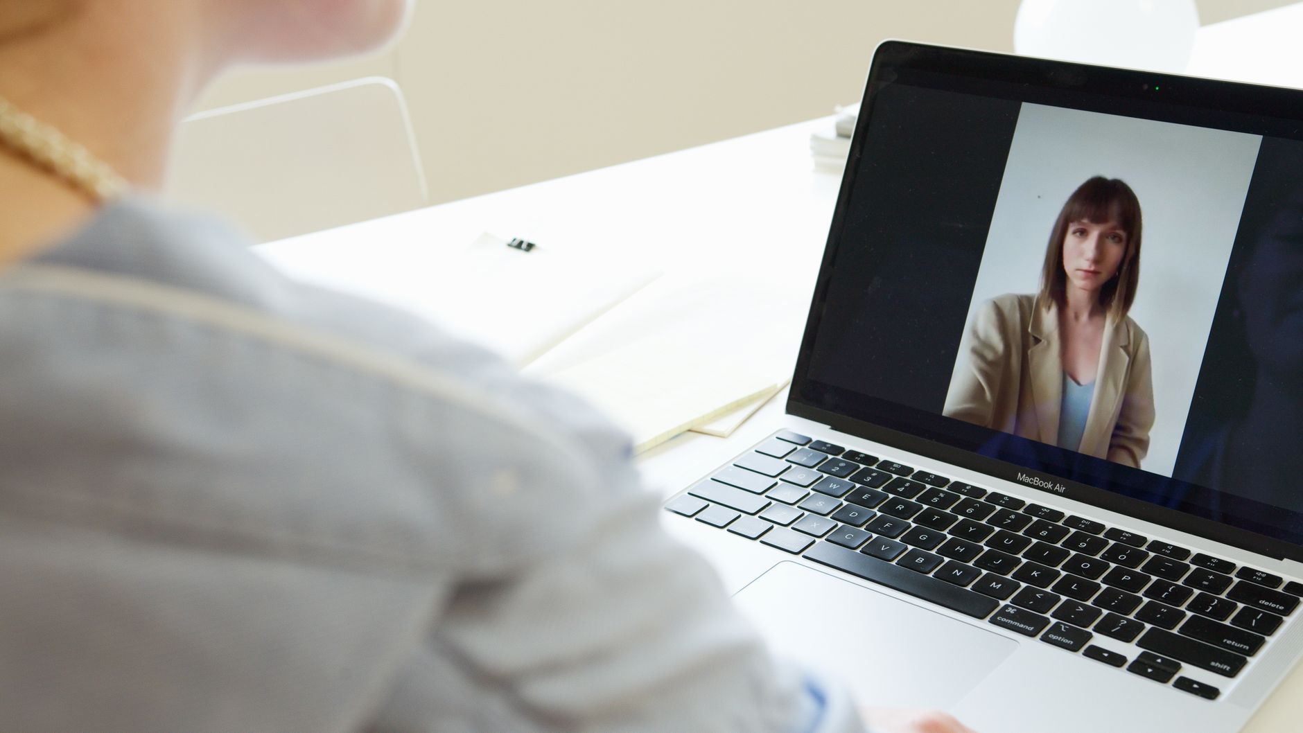 Close-up of woman on a video call using a laptop in a modern workspace.