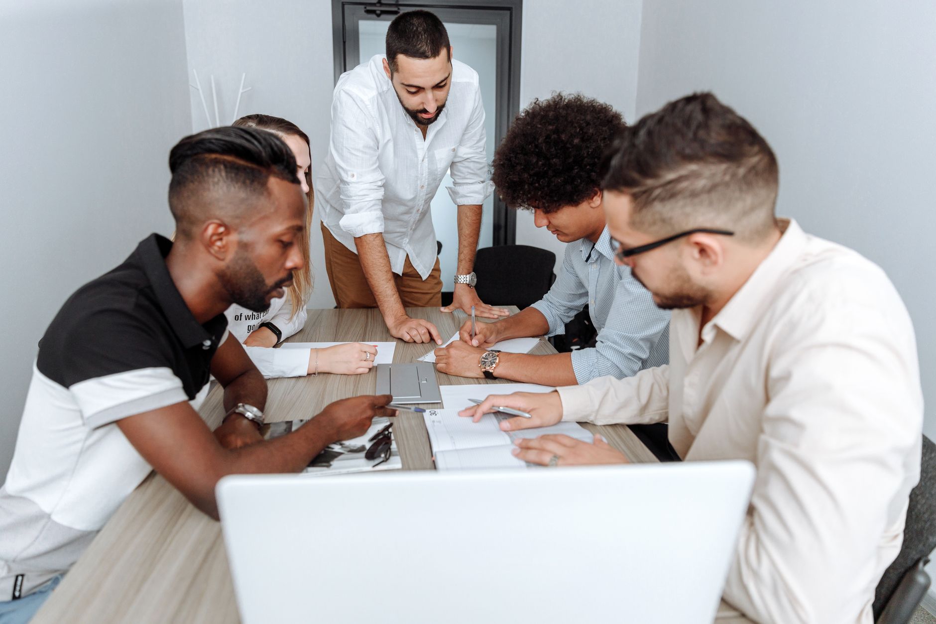 A diverse group of professionals actively collaborating at an office table during a business meeting.