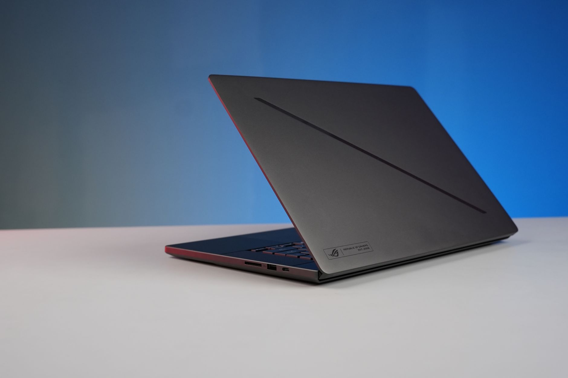 Elegant black laptop on a minimalist desk with a gradient blue background, perfect for tech and work concepts.