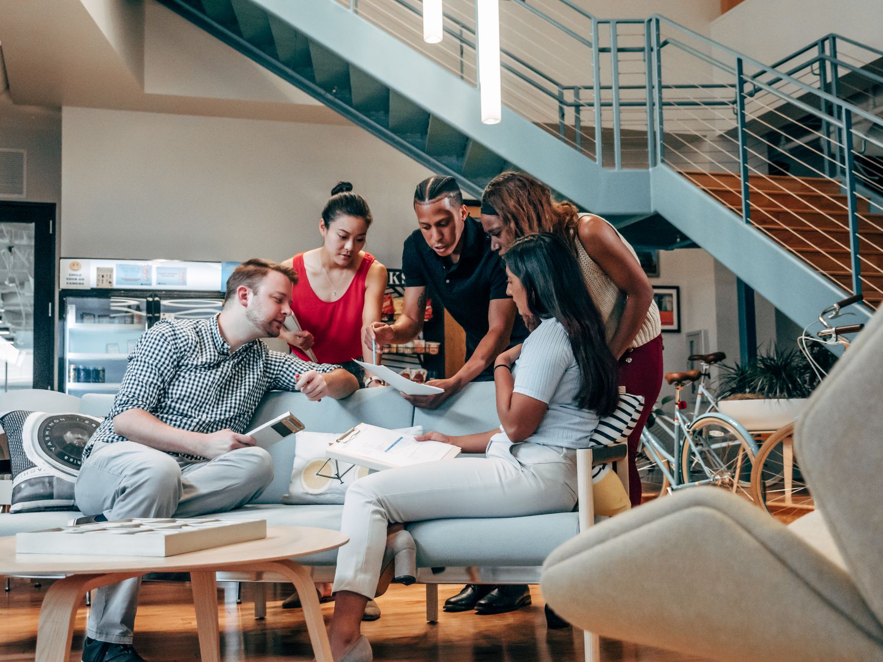A diverse group of coworkers engaged in brainstorming and planning in a modern office lobby.