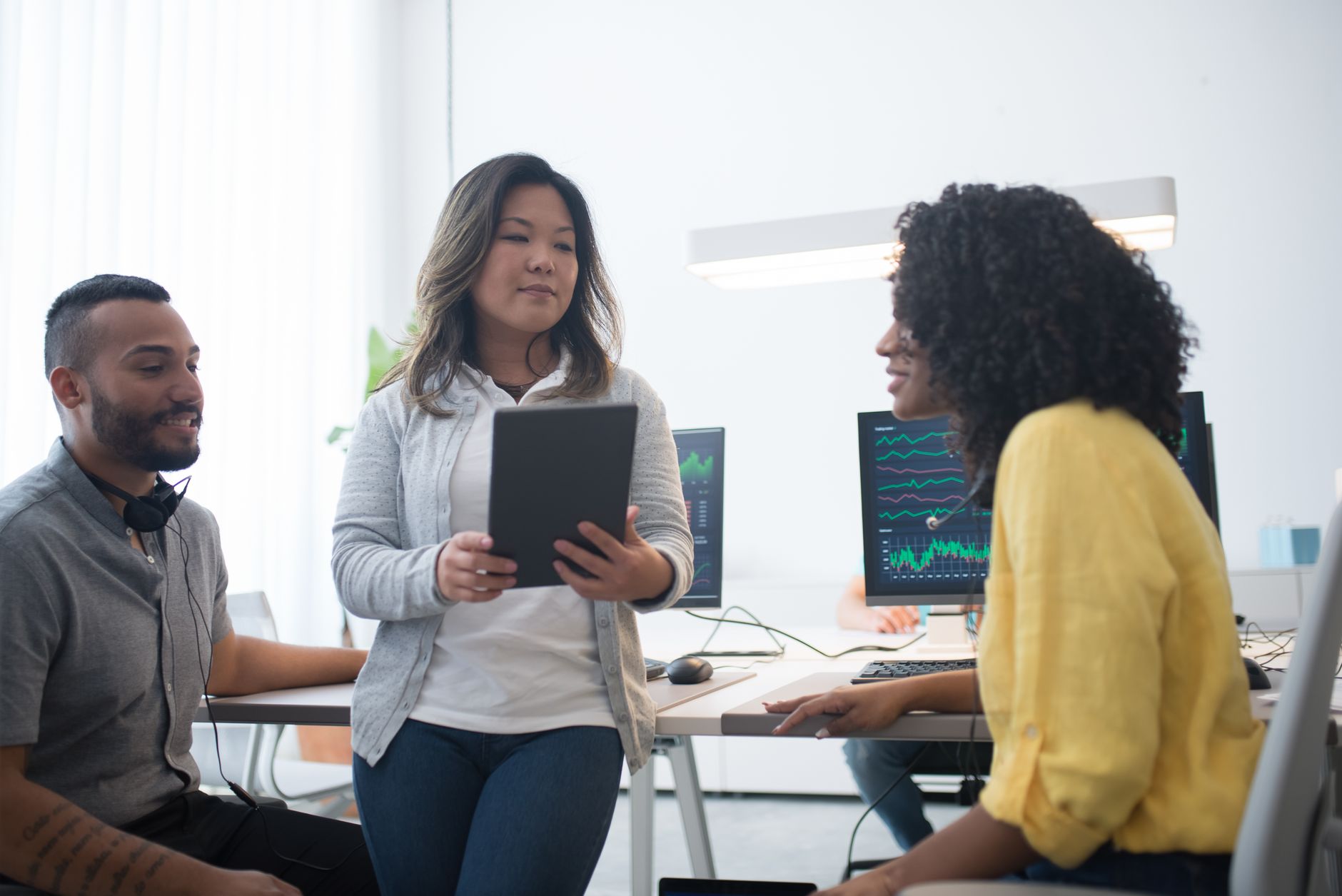 Diverse team working in a modern office with digital screens displaying data.