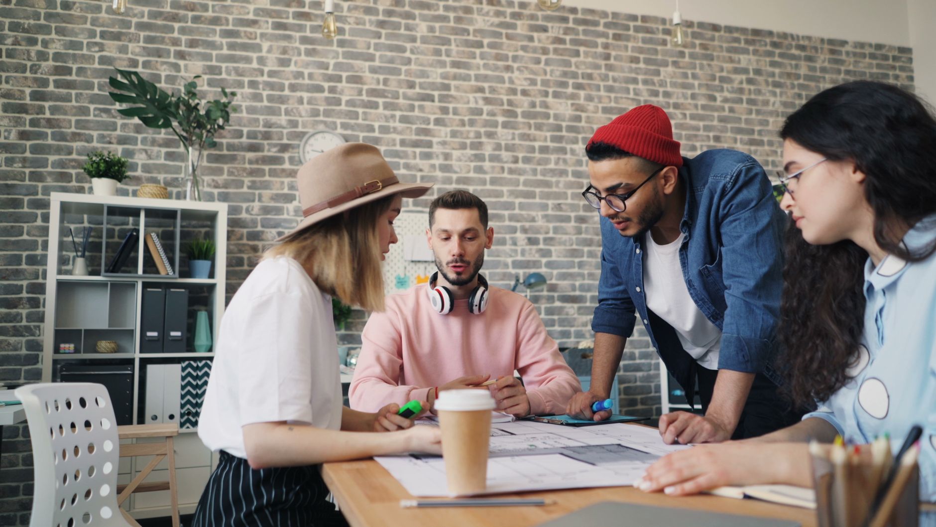 Young diverse team collaborating in modern office setting, engaged in creative brainstorming session.