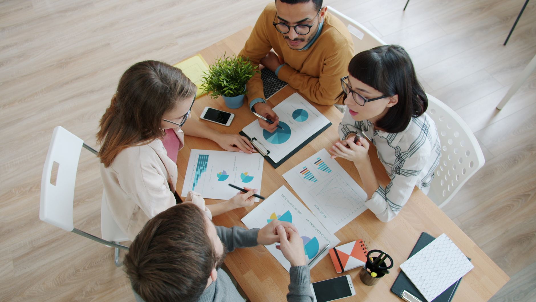 Aerial view of diverse team brainstorming with charts and graphs on table.