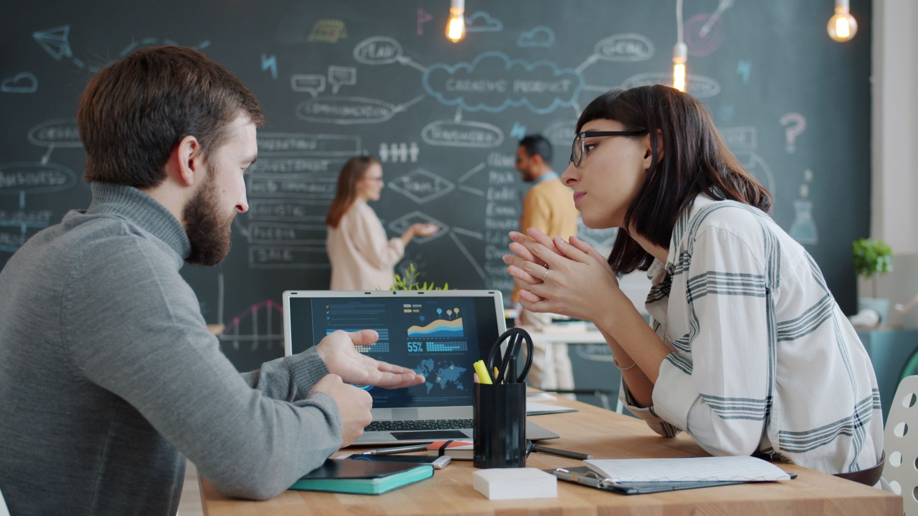 Young professionals collaborating in a creative office space with a chalkboard wall.