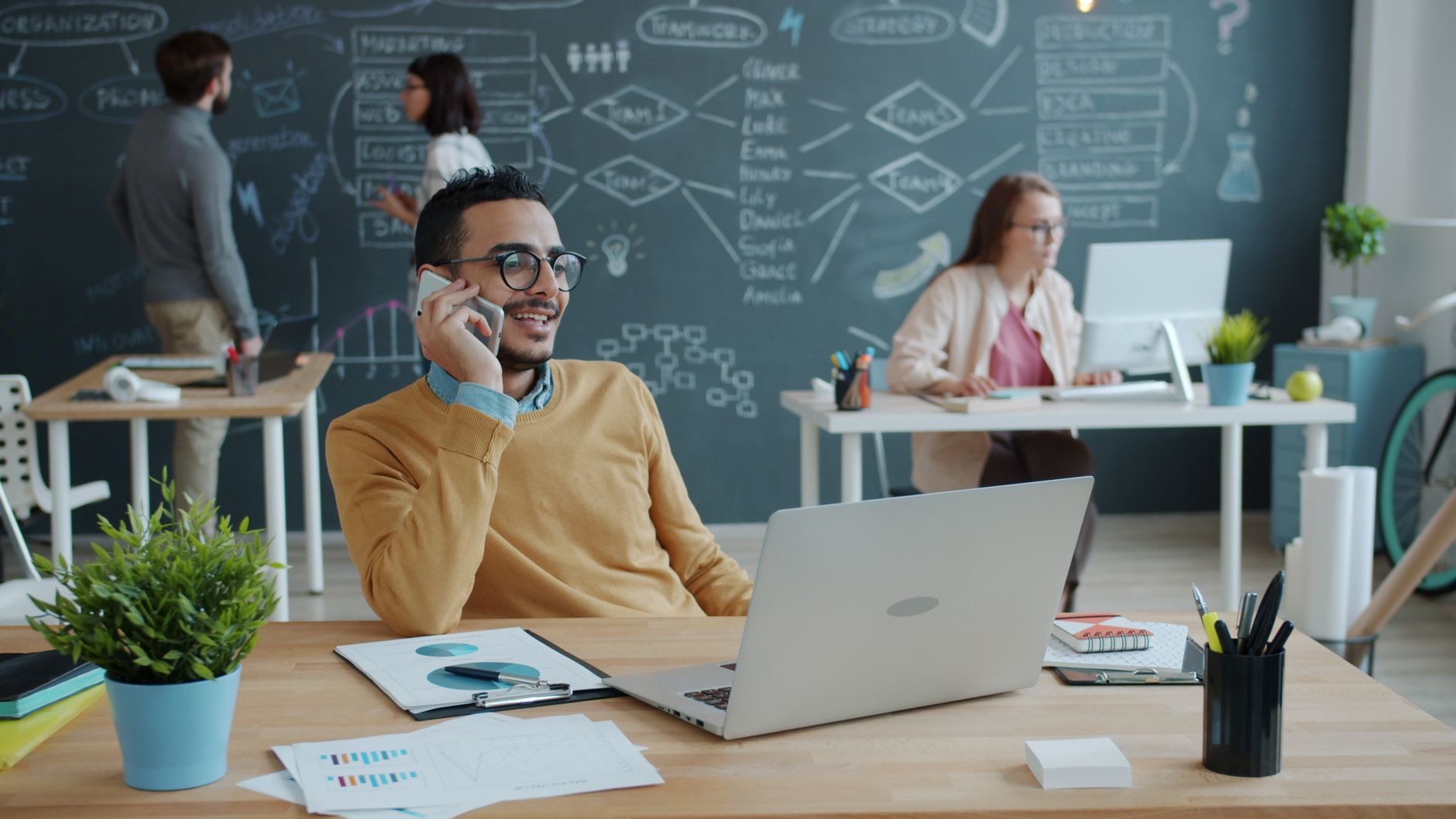 Young professionals collaborating in a stylish office with a chalkboard in the background.