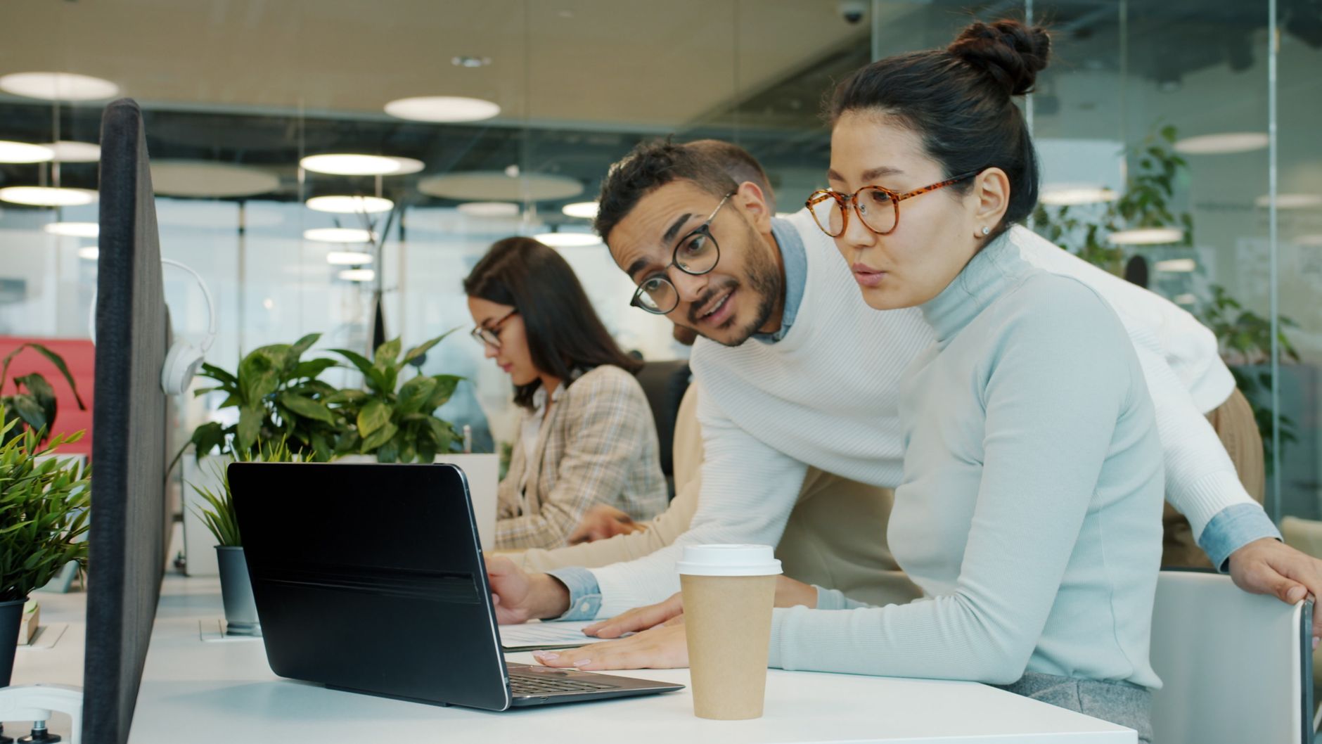 Team collaboration in a modern office with laptops and coffee.