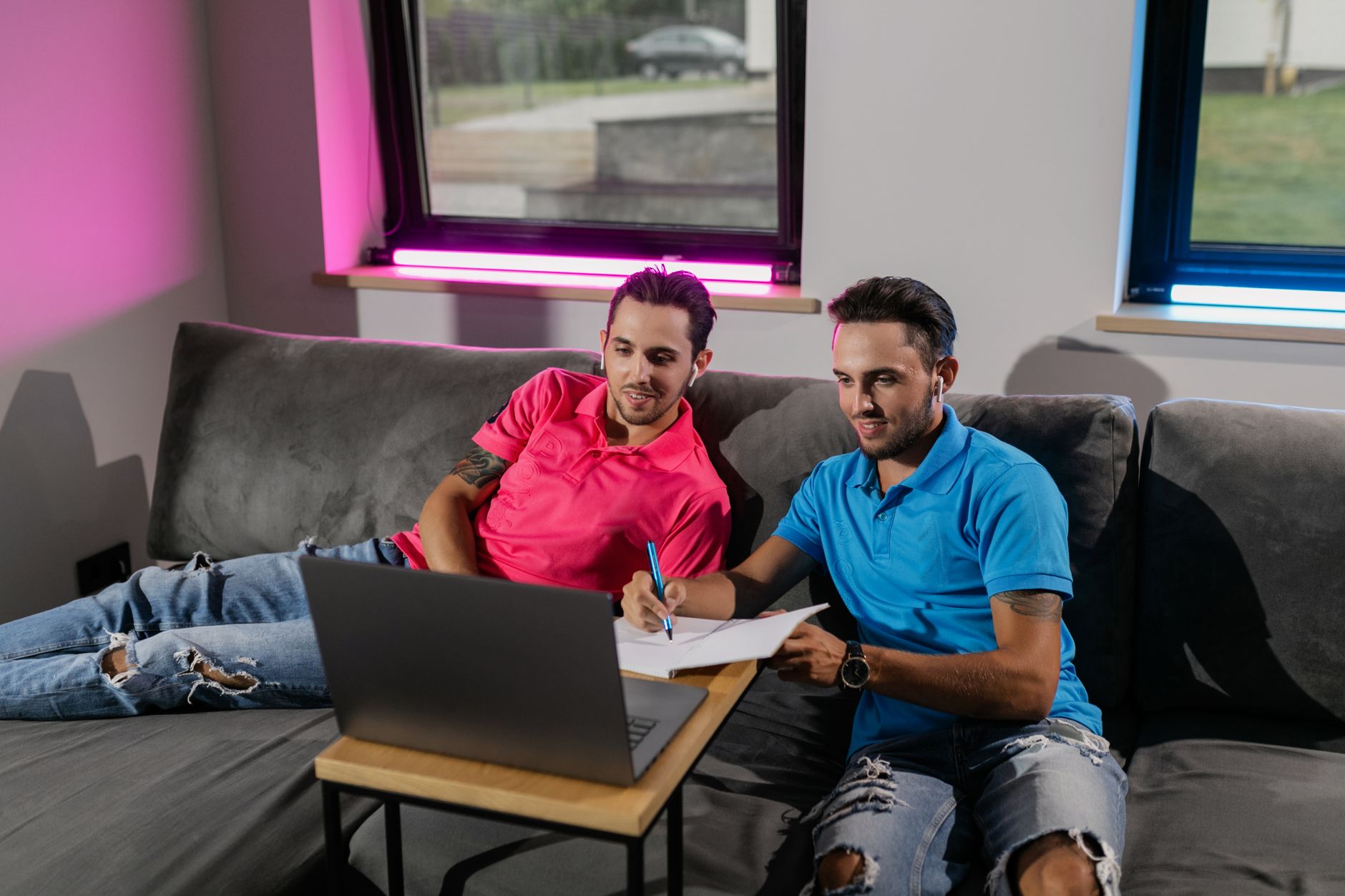 Two young men studying on a laptop at home, showcasing online education.