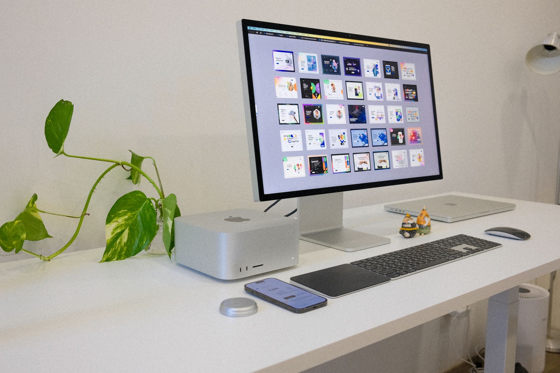 A sleek and modern workstation featuring Apple devices and a touch of greenery, ideal for tech enthusiasts.