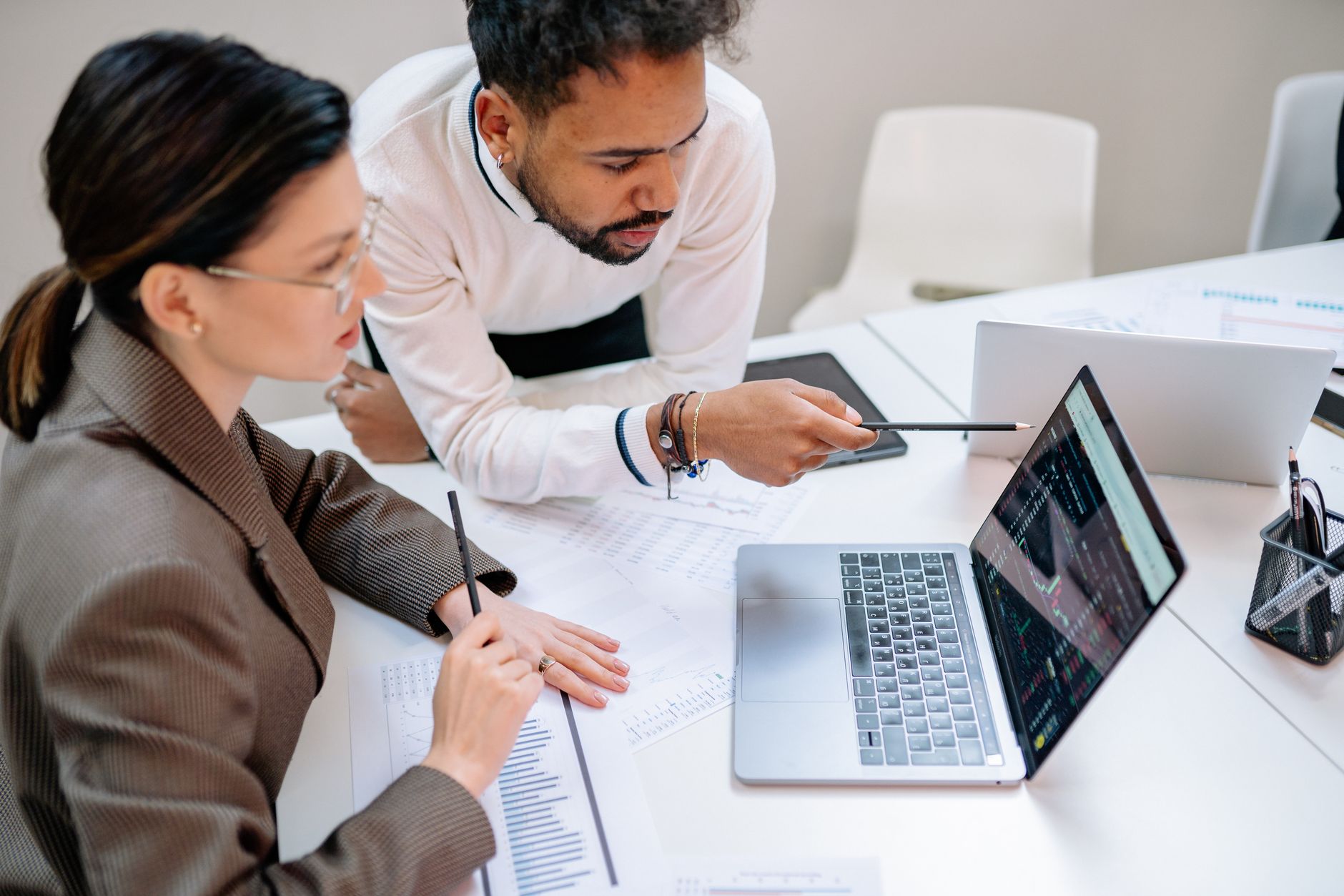 Business professionals discussing data at a desk with a laptop.