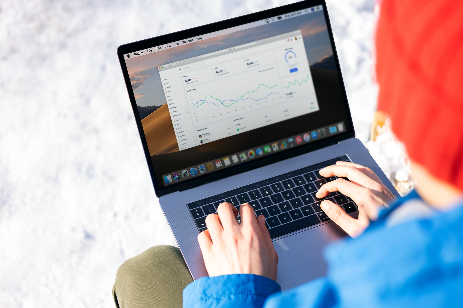 A person in a blue jacket analyzing business analytics on a laptop outdoors during winter.