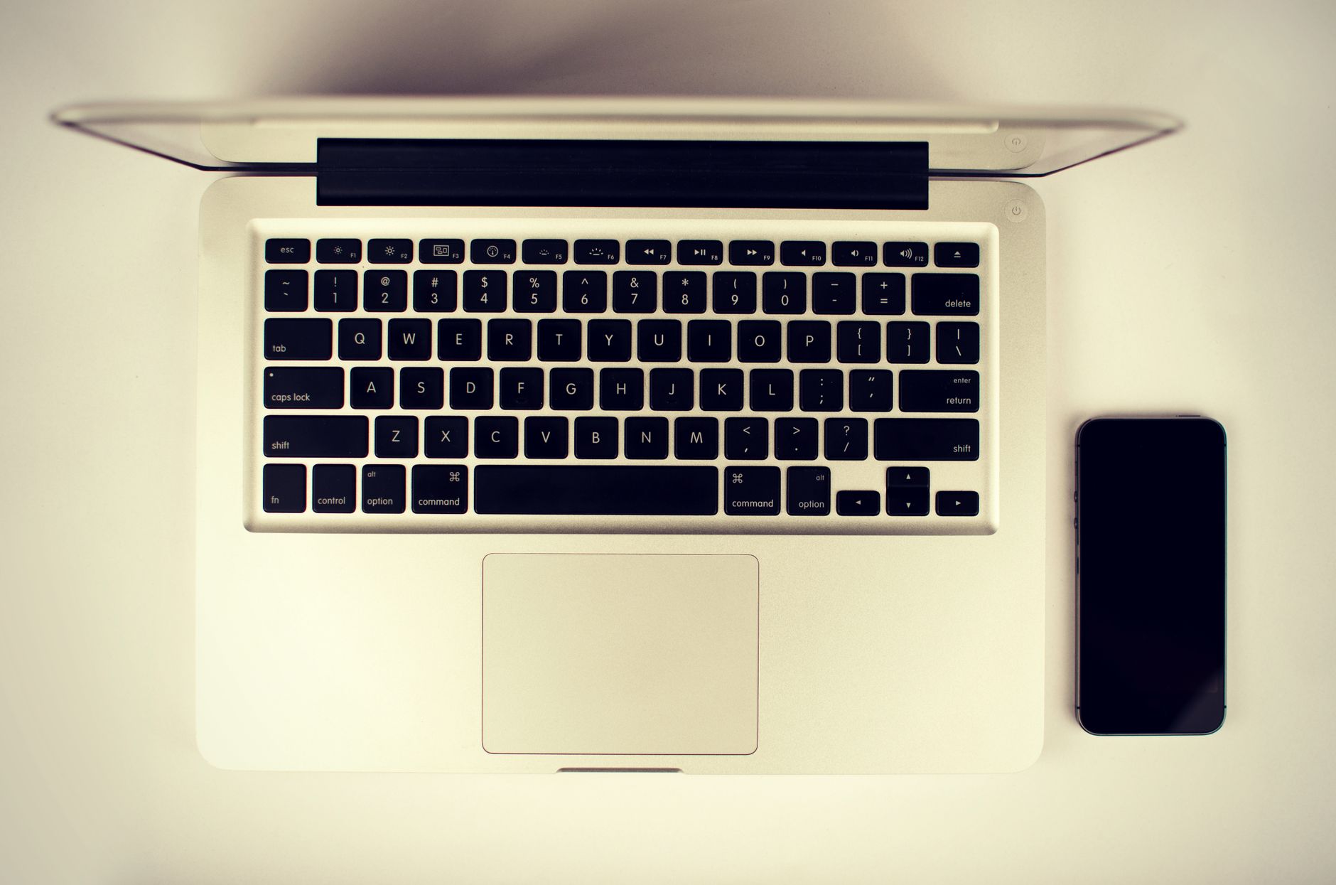 Aerial view of a modern workspace setup featuring a laptop and smartphone on a desk.