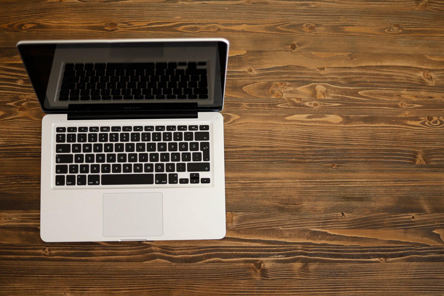 Aerial view of an open laptop on a rustic wooden desk, ideal for technology themes.