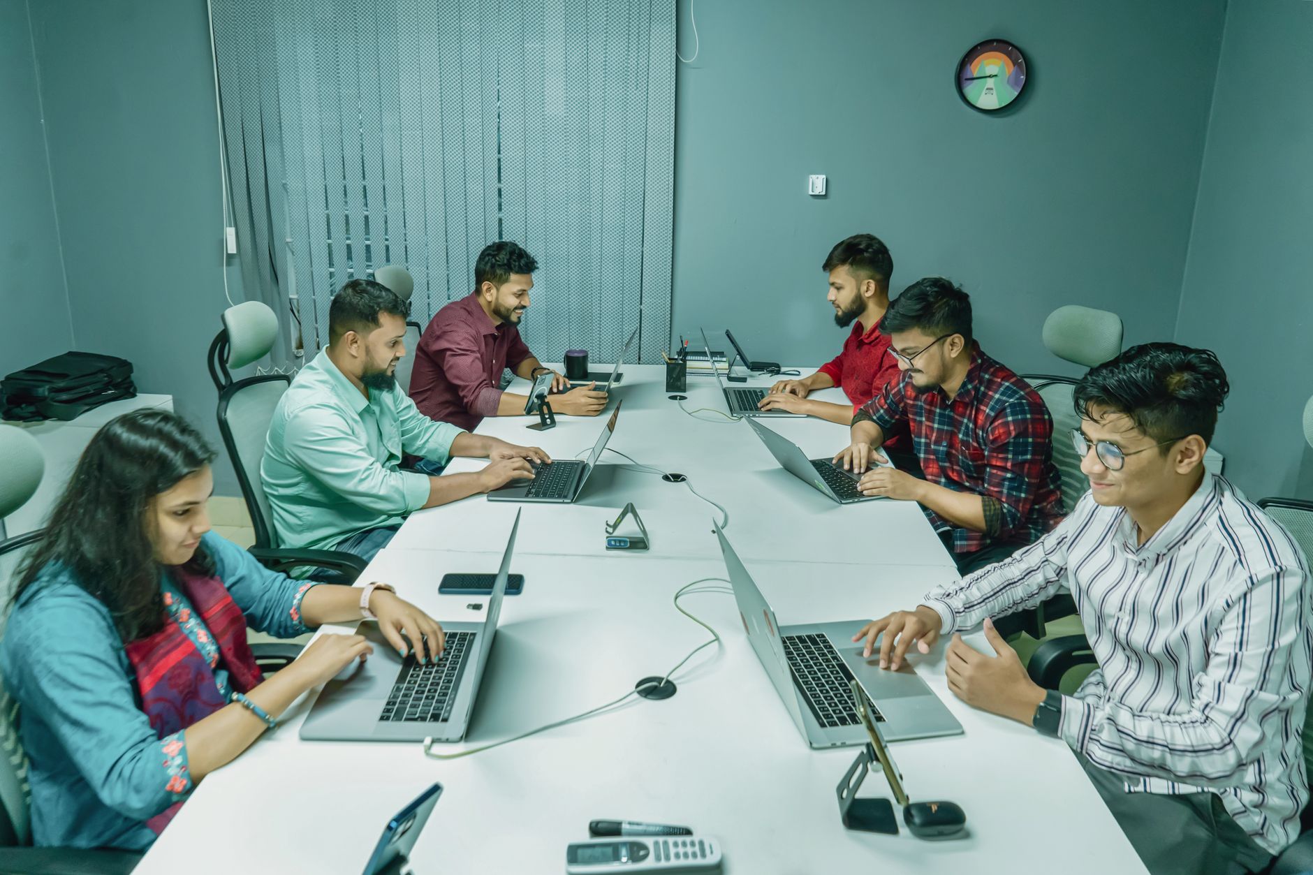 A group of professionals working together on laptops in a modern office setting.