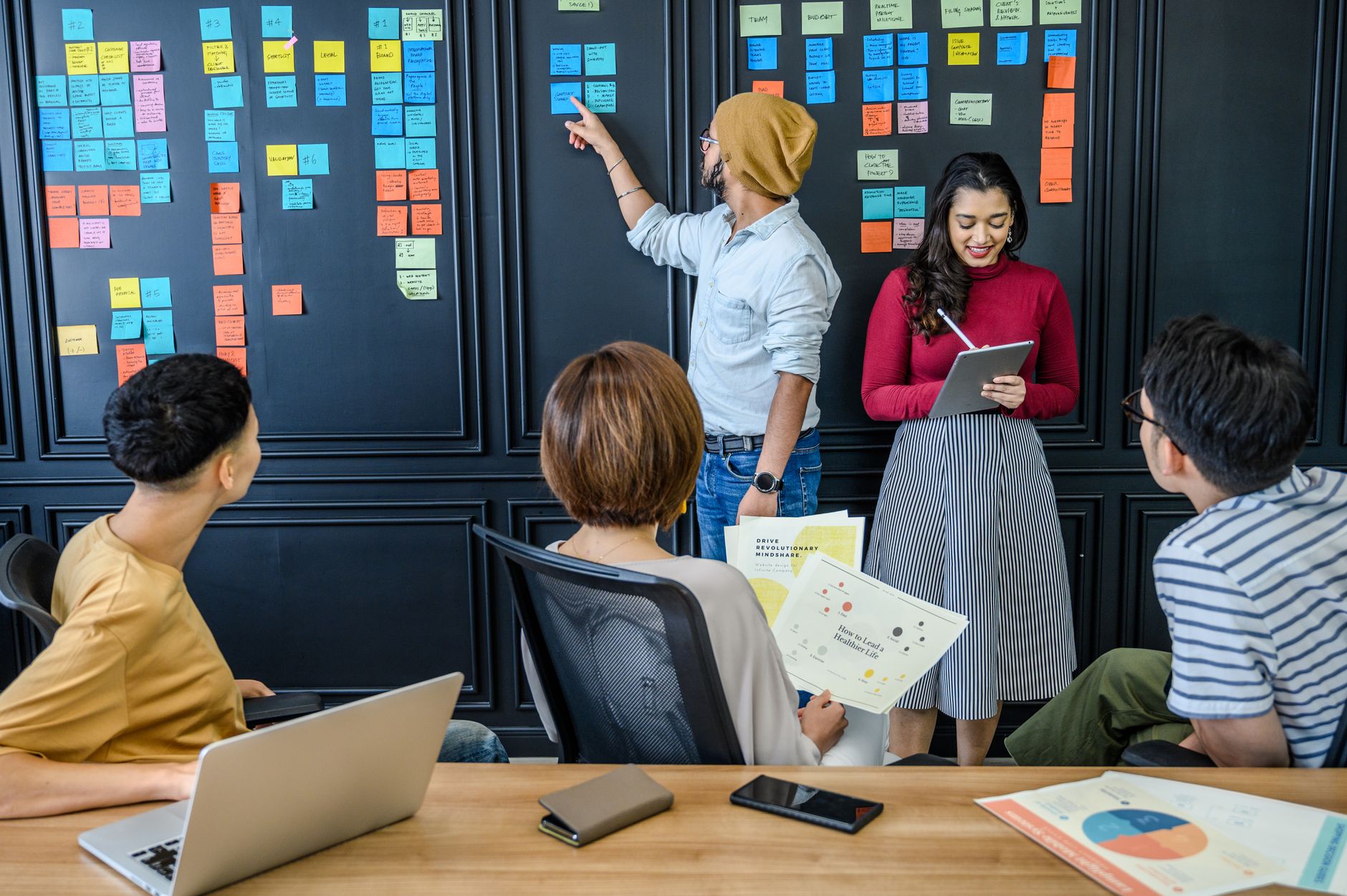 A diverse group collaborating with sticky notes in a modern office setting, fostering creativity and teamwork.