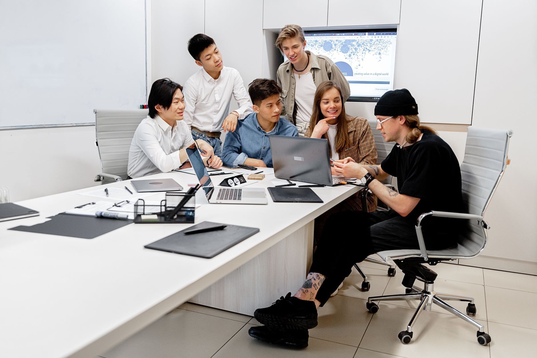 A diverse group of young professionals collaborating on a project in a bright modern office environment.