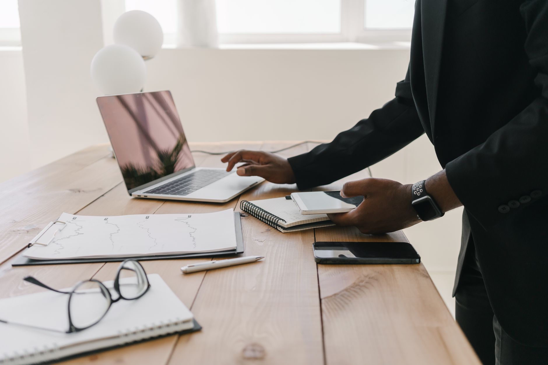 Professional workspace with a laptop, documents, and stationery on a wooden table.