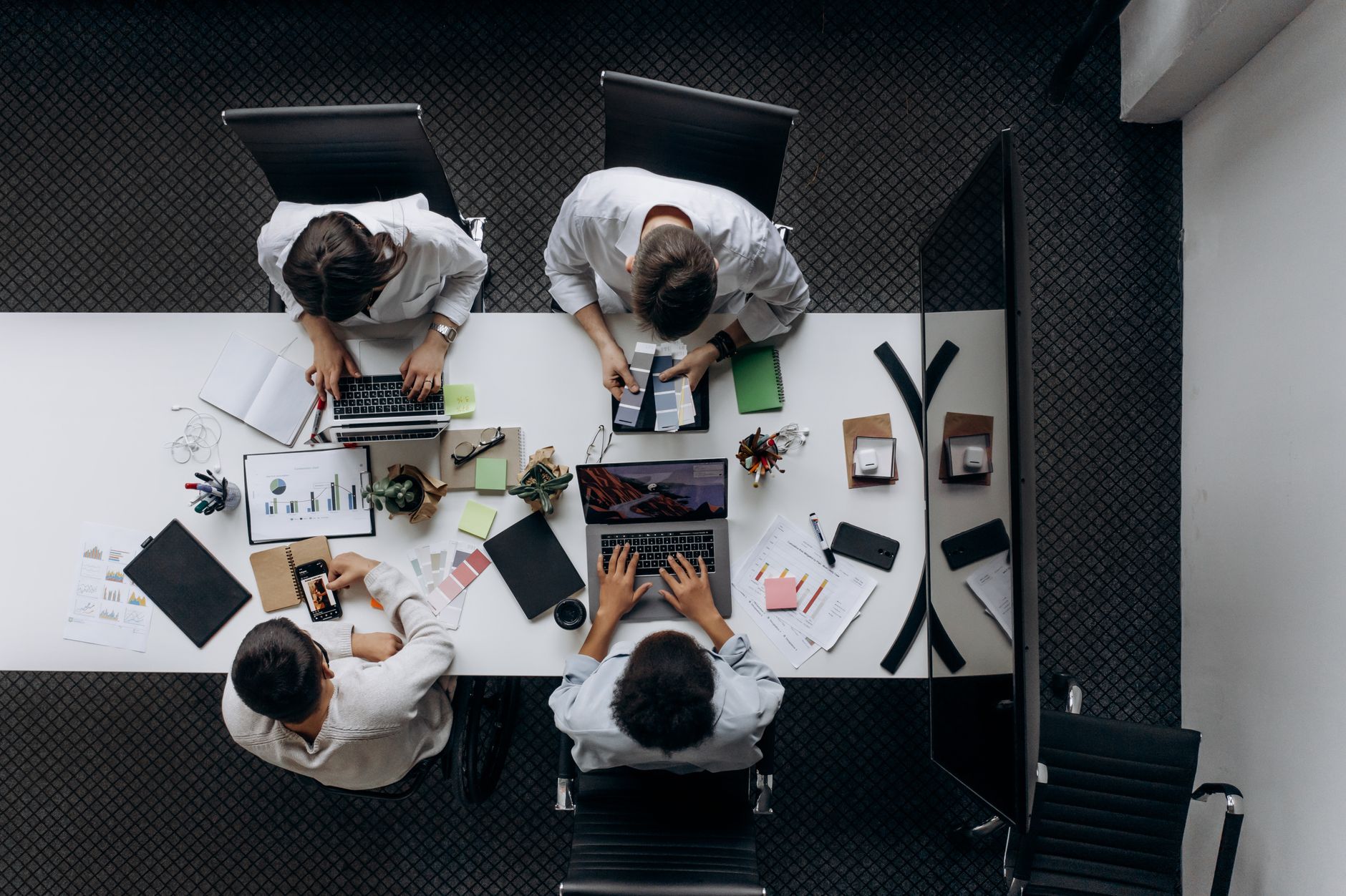 Teamwork in modern office with laptops, charts, and electronic devices from above.