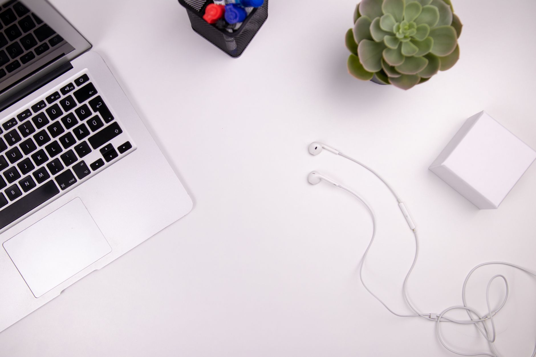 A clean workspace featuring a laptop, succulents, and earphones, perfect for remote work inspiration.