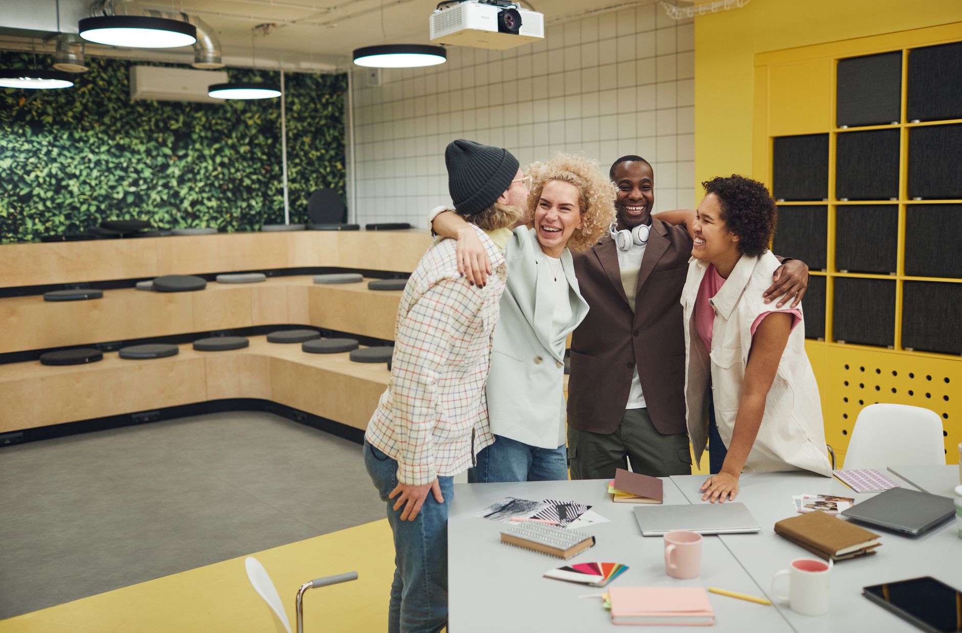 A diverse group of cheerful coworkers hugging in a modern office setting.