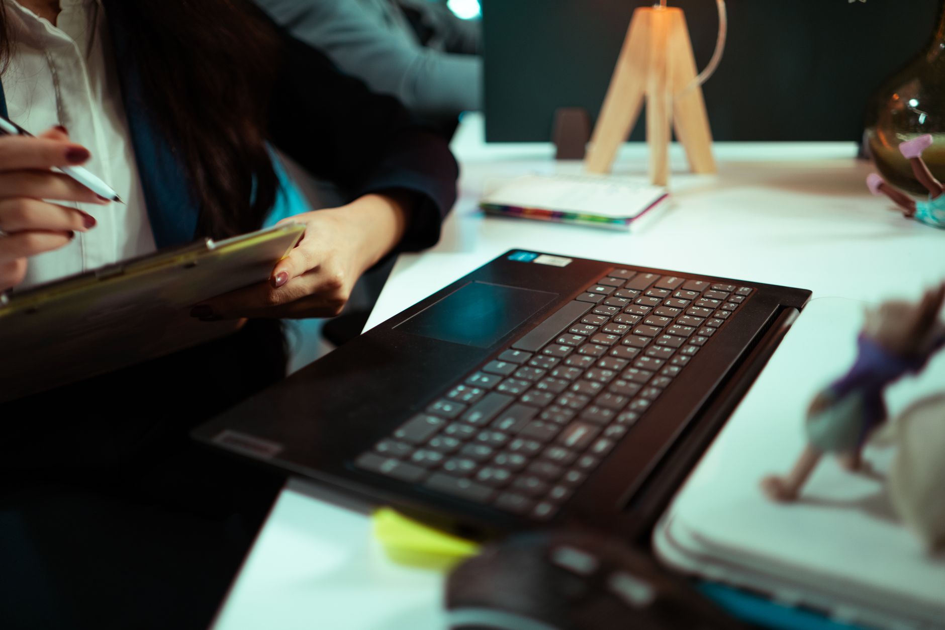 Businesswoman taking notes while working on a laptop in an office.