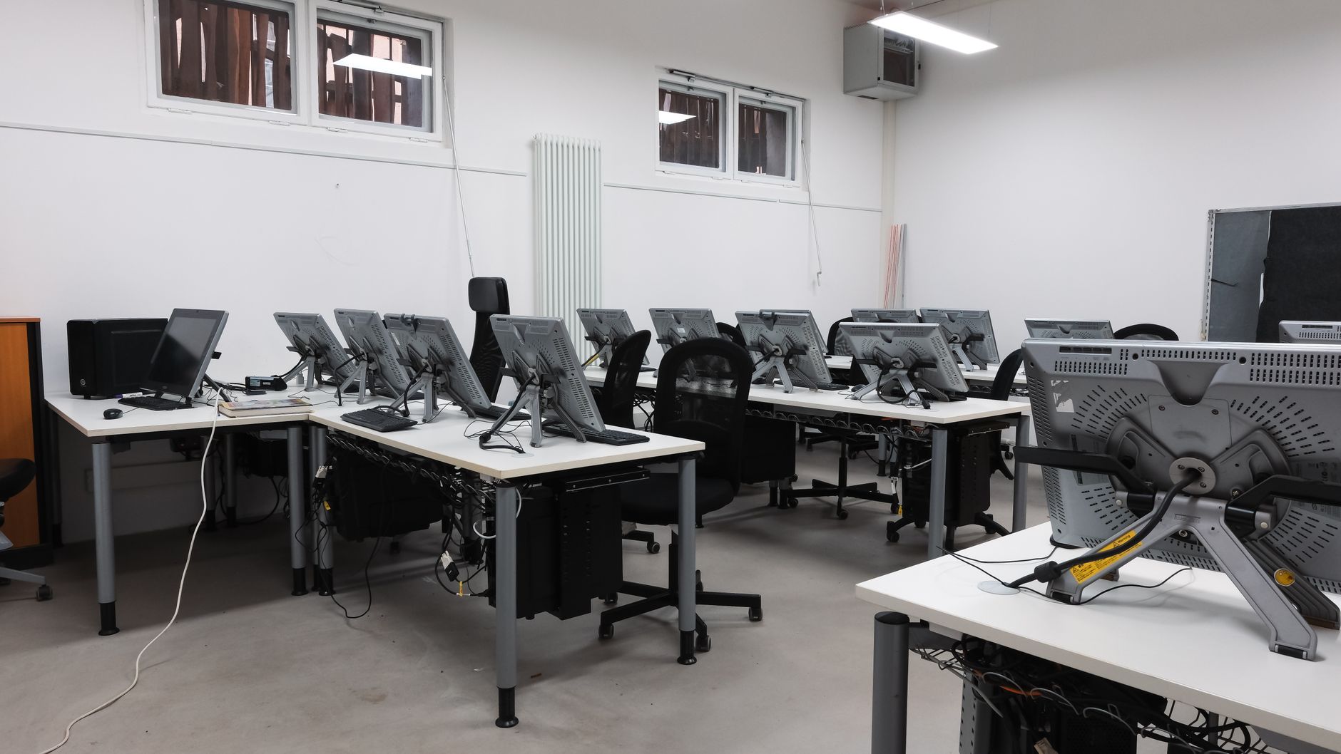 An empty computer lab featuring multiple vacant workstations with modern monitors.