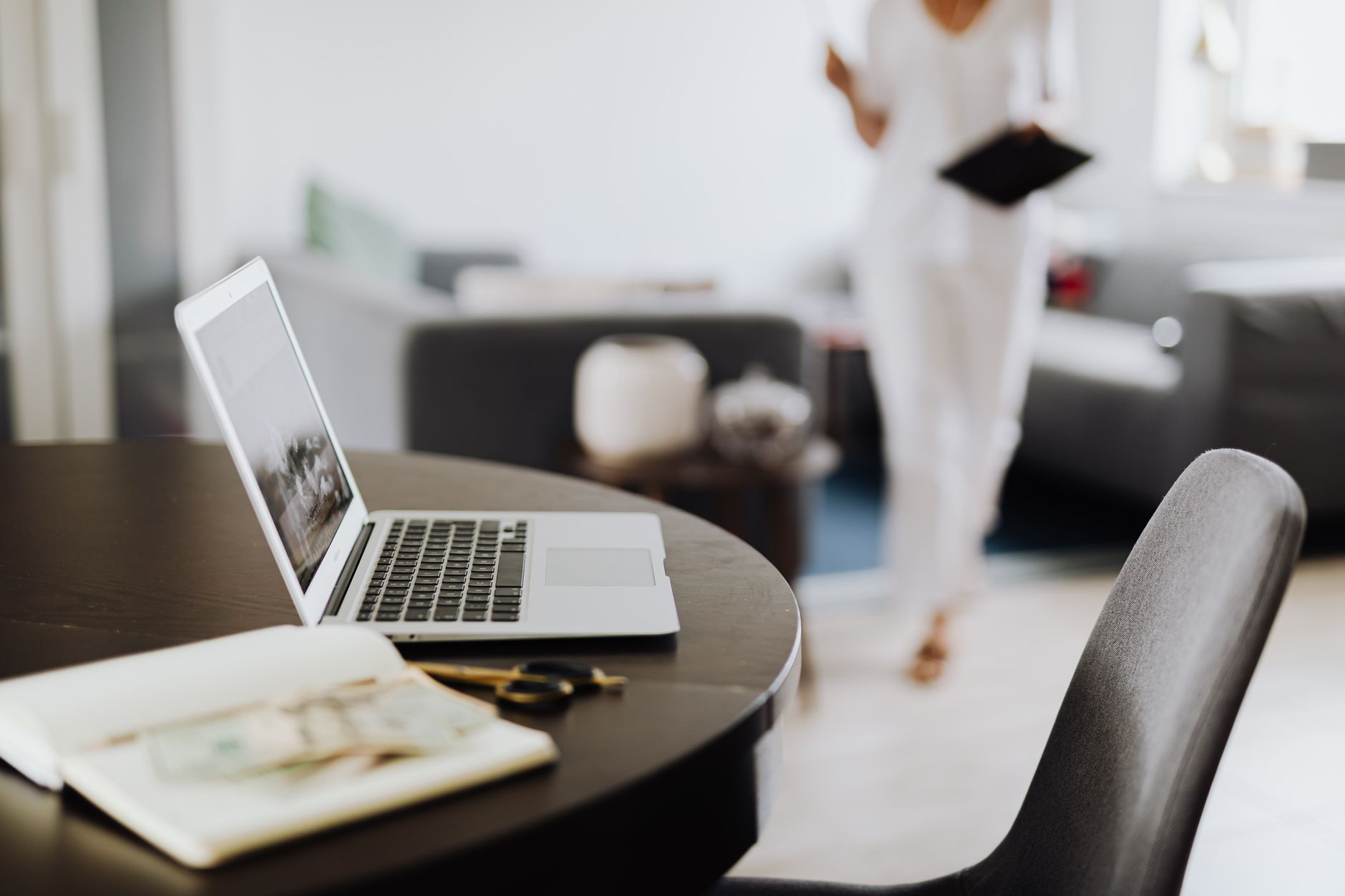 Contemporary workspace featuring laptop, notebook, and blurred person in office setting.