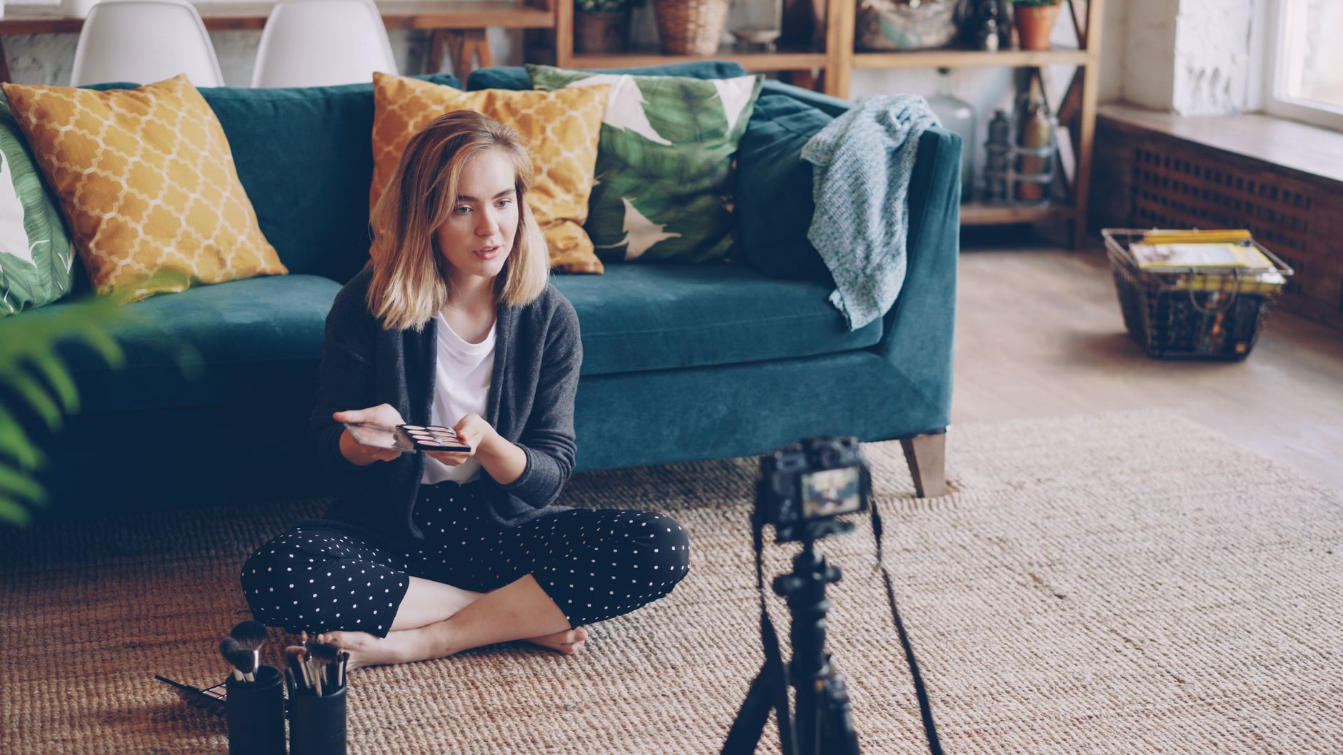 Woman recording a makeup tutorial video in a stylish, comfy living room.