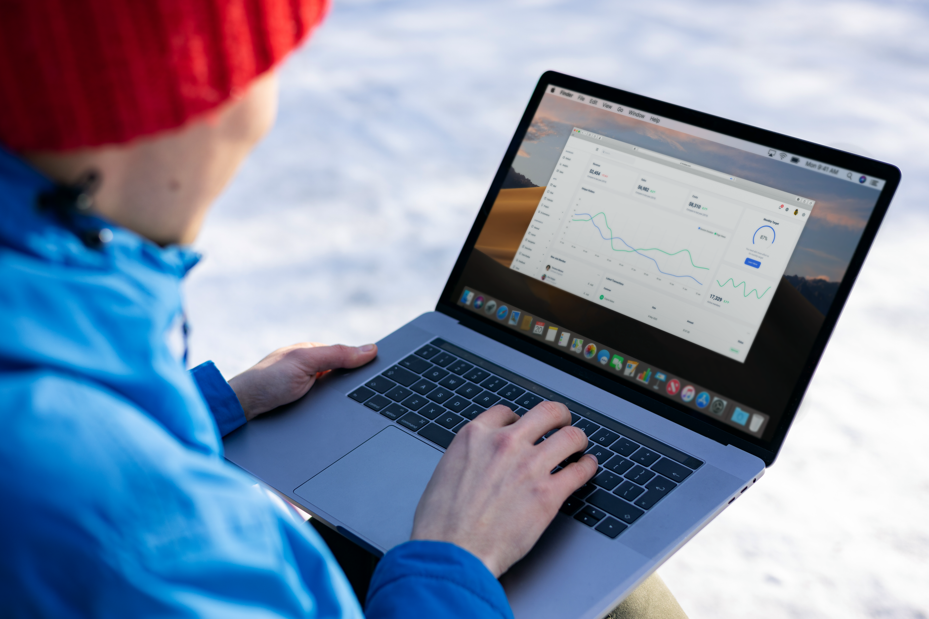 Person working on a laptop analyzing charts in an outdoor setting during winter.