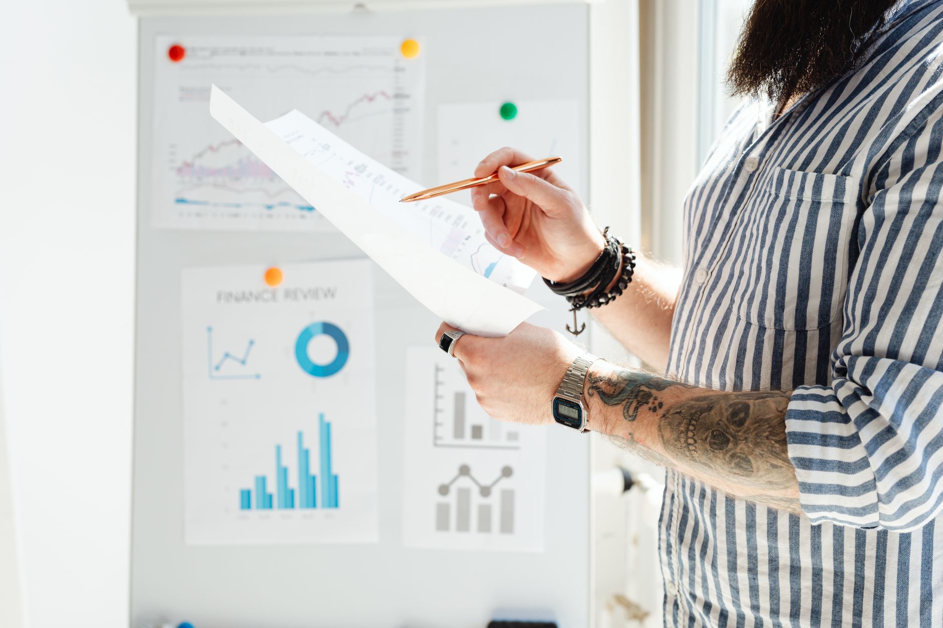 Professional reviewing financial graphs and documents in a bright office setting.